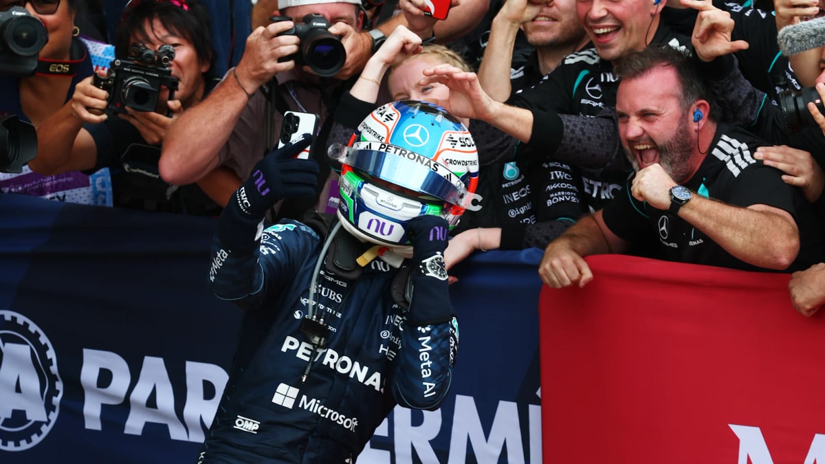 Kimi Antonelli in his Mercedes helmet celebrates with cheering team members after winning the race
