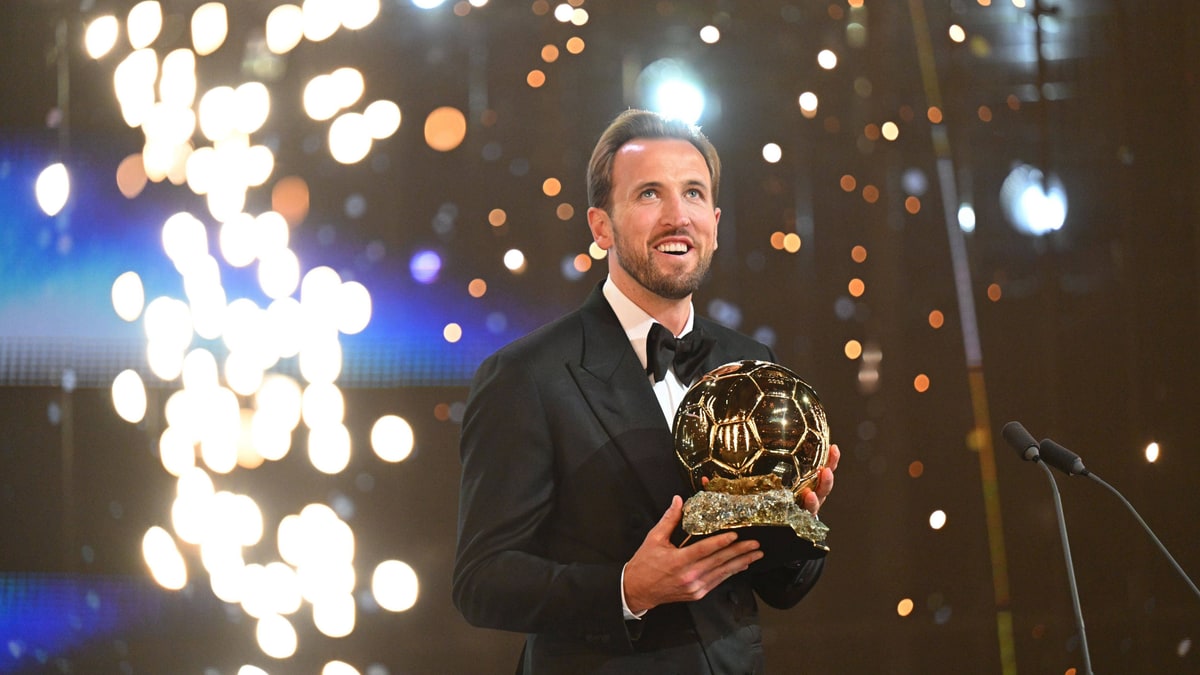 Harry Kane in a tuxedo holding the Ballon d'Or trophy on stage in London