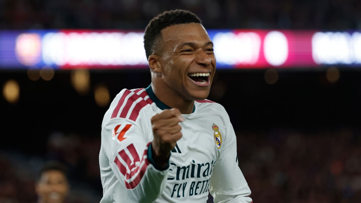 Kylian Mbappe in Real Madrid's white kit celebrates a goal at Camp Nou