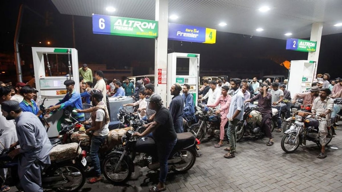 Motorcyclists queue for fuel at a petrol station in Pakistan at night
