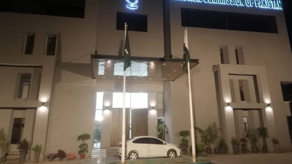 The Election Commission of Pakistan building lit up at night, with Pakistani flags at the entrance