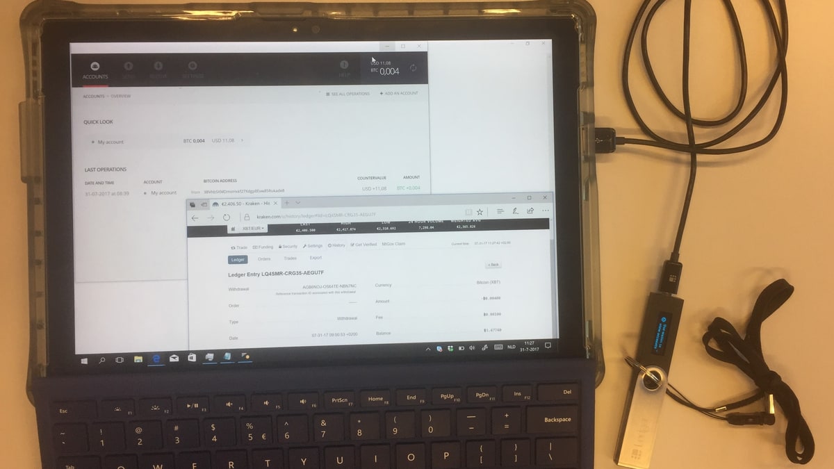 A laptop showing a crypto exchange account next to a hardware wallet plugged in by USB