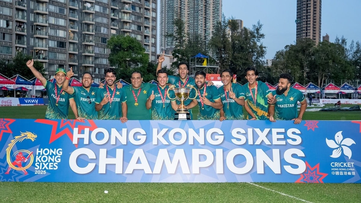 Pakistan squad celebrating with the trophy behind a Hong Kong Sixes 2025 Champions banner