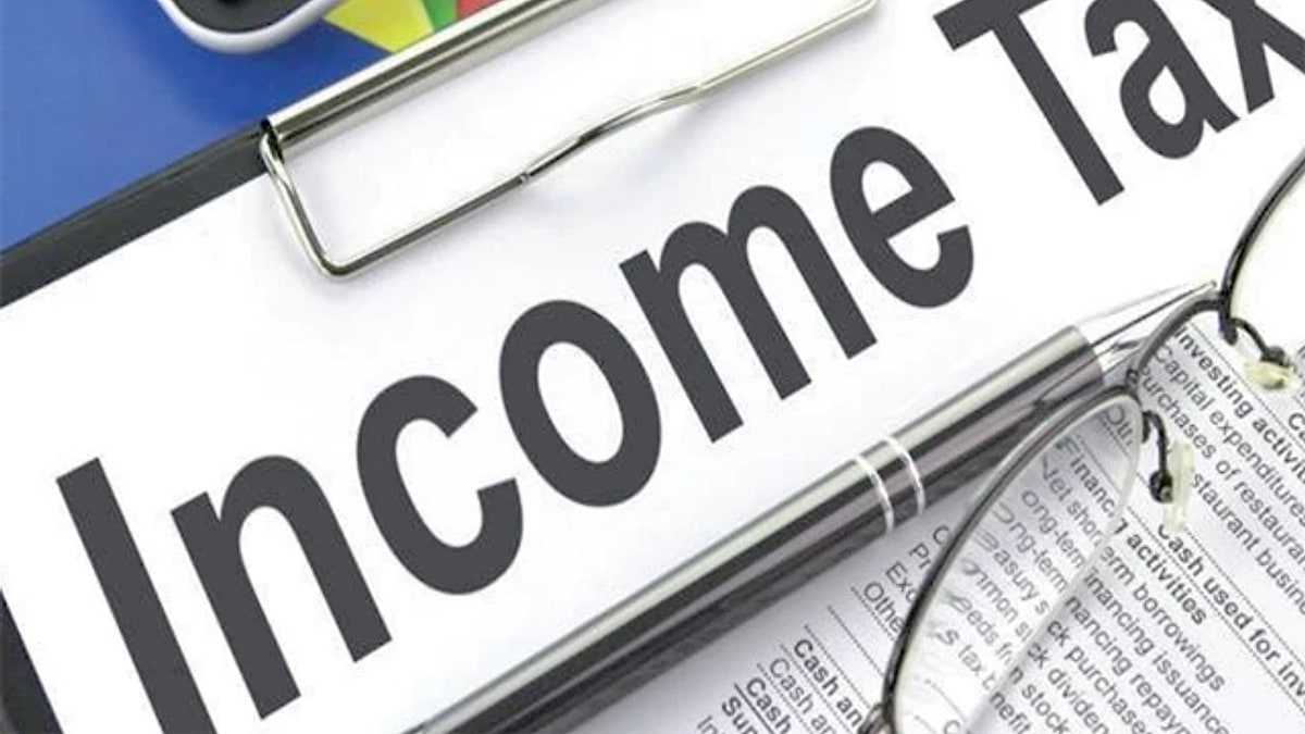 A clipboard reading Income Tax next to a pen, glasses and financial statements