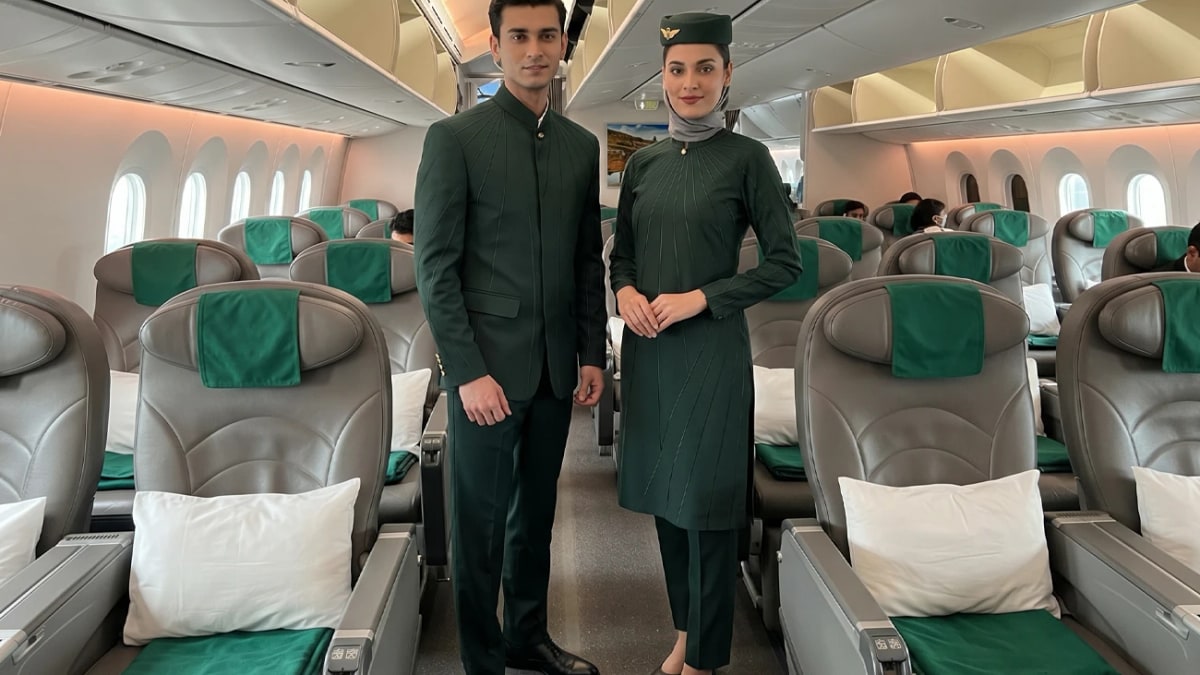 A male and a female PIA crew member in the new dark green HSY uniforms inside a Boeing 787 cabin