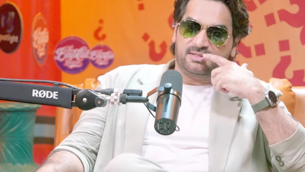 Humayun Saeed in sunglasses speaking into a microphone during his podcast interview with Ali Salman