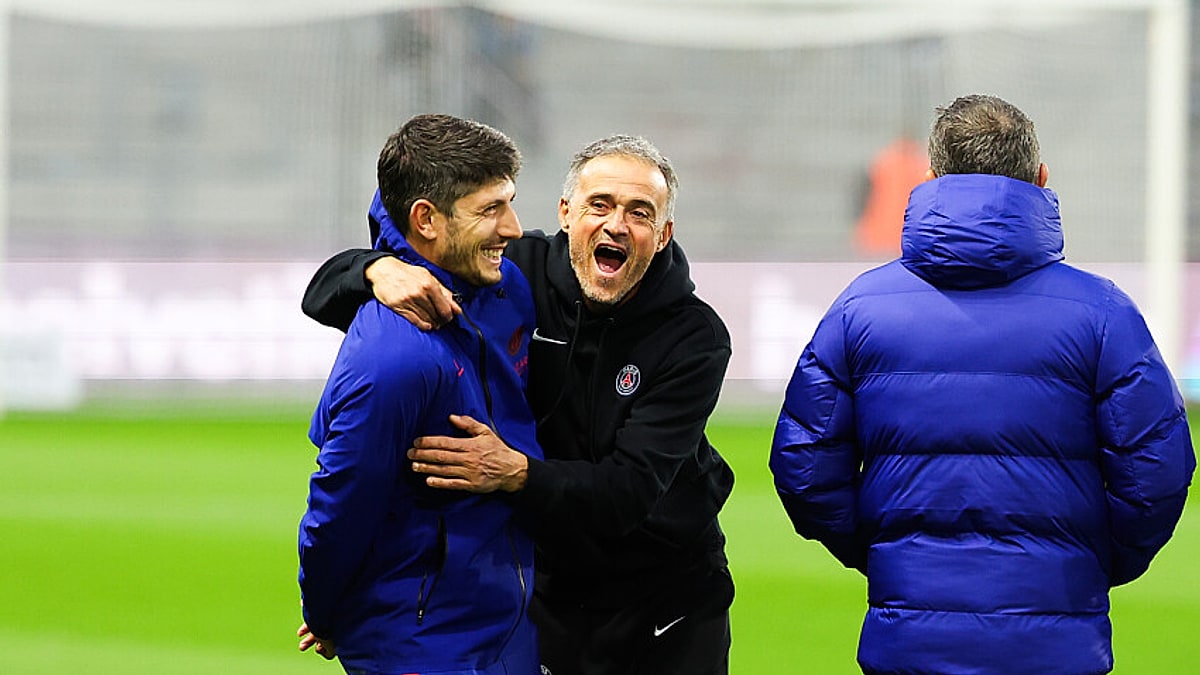 PSG coach Luis Enrique laughs and hugs a member of his staff on the pitch