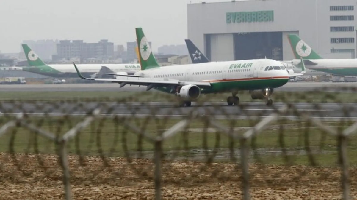An EVA Air plane on the runway at Taoyuan International Airport in Taiwan, seen through a perimeter fence