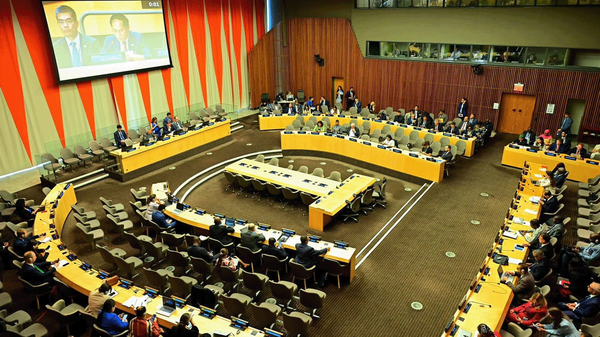 Delegates seated around the tables of a United Nations conference room during a meeting